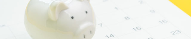 Finance, saving money or salary pay day, white piggy bank on white clean calendar on solid yellow background.