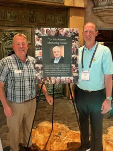 Chuck Wilson, Executive Director of NSCA Education Foundation; and Mike Boettcher, NSCA Board Member and longtime colleague of John's, announce The John Greene Mentorship Award during InfoComm 2023.