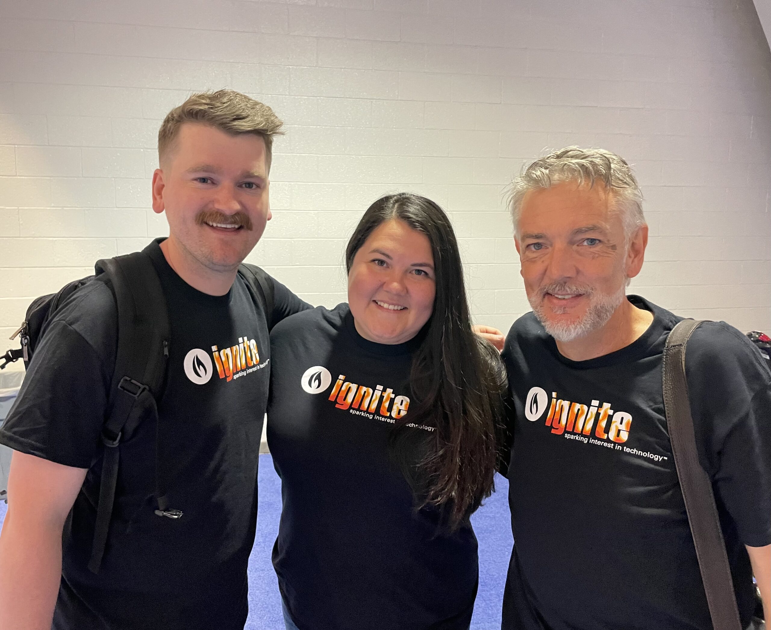 three people smiling with arms around each other